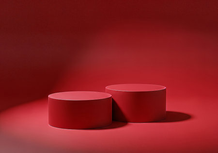 Two vibrant red cylindrical pedestals on a matching red background, illuminated by dramatic spotlighting. Ideal for product showcases, presentations, or abstract concepts.の素材