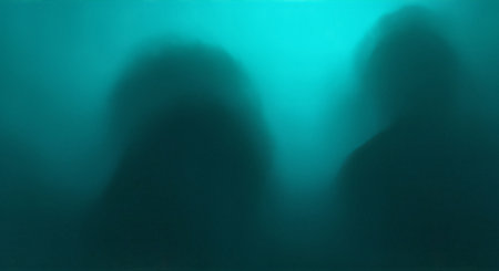 Two dark blurry silhouettes of people in water with blue green background lightの素材