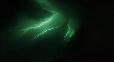 Electric green lightning bolt illuminates a dark stormy night sky with vibrant glowの素材