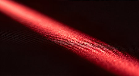 Close-up of a red metallic tube or cylinder with a textured surface on a black backgroundの素材