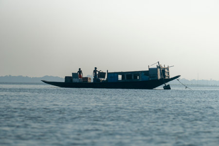 A silhouette of a boat with fishermen on a calm lake In Netrokona, Bangladeshの写真素材