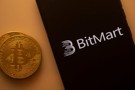 Dhaka, Bangladesh 22 September 2025:Bitcoin beside a smartphone with the BitMart logo on an orange...