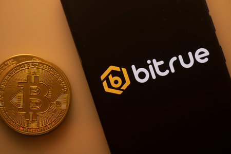 Dhaka, Bangladesh 22 September 2025:Bitcoin coin beside a black phone screen displaying the Bitrue logoのeditorial素材
