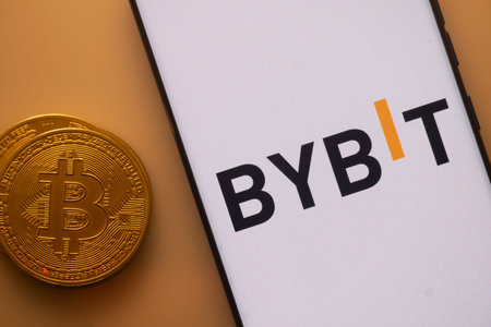 Dhaka, Bangladesh 22 September 2025:Bitcoin near a smartphone featuring the Bybit logo under orange...