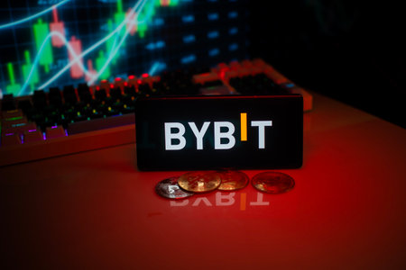 Dhaka, Bangladesh 18 September 2025:BYBIT logo on phone with a red glow, coins, and stock chart, suggesting a trading focusのeditorial素材
