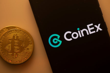 Dhaka, Bangladesh 22 September 2025:CoinEx logo displayed on a smartphone screen near a Bitcoin coin on an orange backgroundのeditorial素材