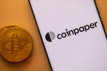 Dhaka, Bangladesh 22 September 2025:Bitcoin next to smartphone with Coinpaper app interface on white...