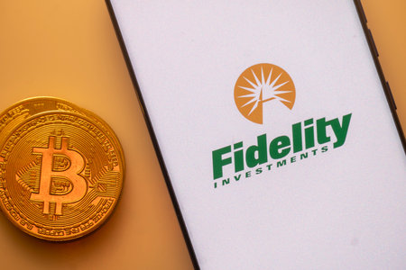 Dhaka, Bangladesh 22 September 2025:Bitcoin coin next to a smartphone displaying the Fidelity Investments logo on a light backgroundのeditorial素材