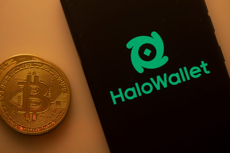 Dhaka, Bangladesh 22 September 2025:Bitcoin coin alongside phone showcasing HaloWallet logo on black...