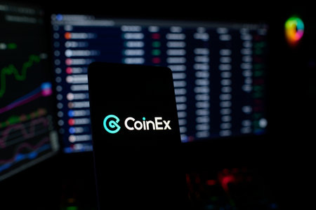 Dhaka, Bangladesh 26 September 2025:CoinEx logo on a smartphone, trading screens visible behindのeditorial素材
