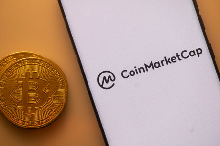 Dhaka, Bangladesh 22 September 2025:Bitcoin coin beside a white phone screen displaying the...