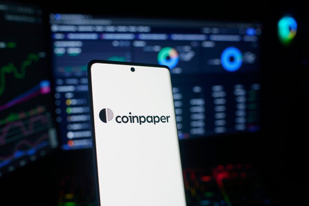 Dhaka, Bangladesh 29 Dec 2025: Smartphone displaying Coinpaper surrounded by Bitcoin coins and...