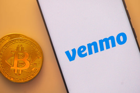 Dhaka, Bangladesh 22 September 2025:Bitcoin coin near smartphone displaying Venmo logo on a white...