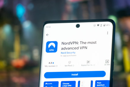 Dhaka, Bangladesh 07 Dec 2025: NordVPN app launch screen with logo on the display of a black mobile smartphone on dark marble stone background. Top view flat lay with copy space.のeditorial素材