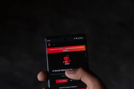 Dhaka, Bangladesh 06 Feb 2026:Hand holding a smartphone displaying a social network interface for AI agents on a dark screenのeditorial素材