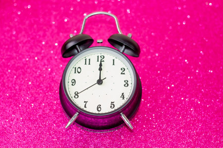 Vintage alarm clock on pink glitter background. Time concept. Copy space.の写真素材