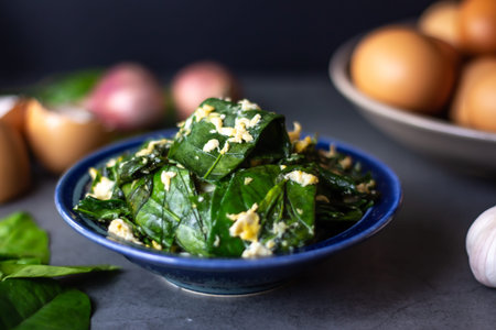 Stir-fried spinach leaves with garlic and eggs in a bowl