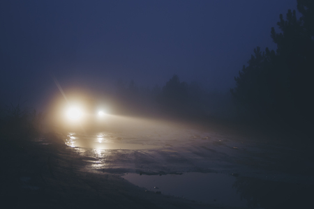 Car on dirty road in strong haze fog at twilightの写真素材