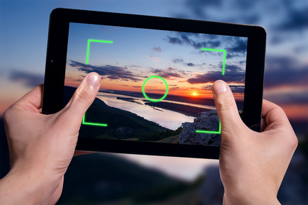 Hold black tablet on hands. Shooting nature landscapeの写真素材