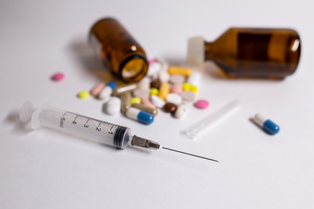 Medicine pills and syringe on a white backgroundの写真素材