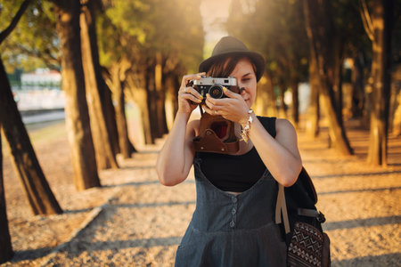 Woman with vintage camera in park alley at sunset