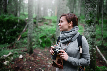 Woman with vintage camera taking photo in the forestの写真素材