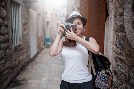 Woman traveler with vintage camera taking photo at old townの写真素材