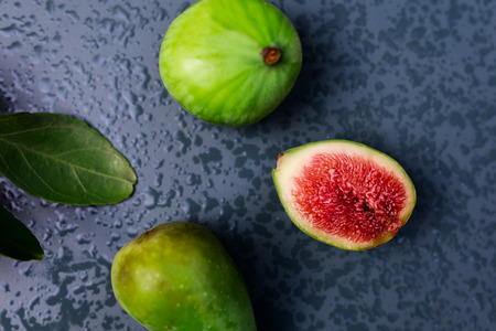 Green figs on wet metal table flat viewの写真素材