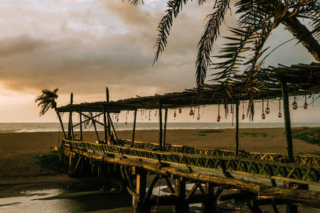 Beautiful sunset at tropical island restaurant resort. Vintage light bulbs, film color toned filterの写真素材