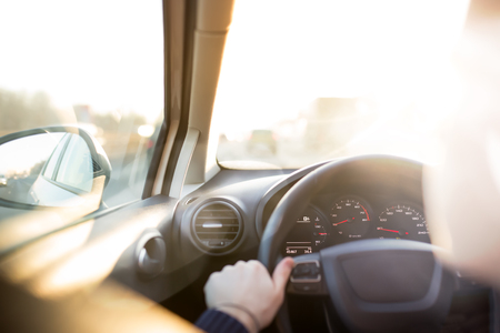 Man is driving car at sunset. Inside interior view. Hands on steering wheelの写真素材