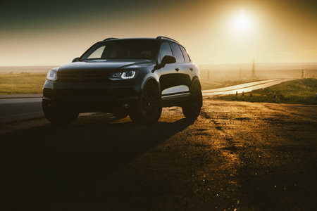 Saratov, Russia - June 07, 2018: Black car Volkswagen Touareg is parked at countryside asphalt road near highway at golden sunsetのeditorial素材