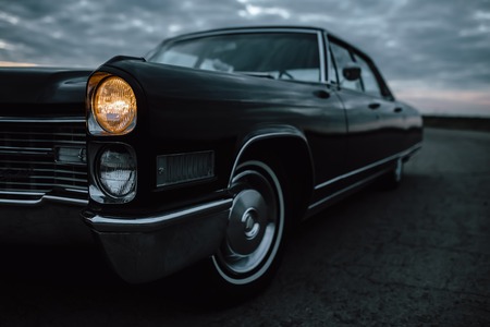 Engels, Russia - June 08, 2018: Black retro vintage muscle car Cadillac Fleetwood Brougham is parked at countryside asphalt road at duskのeditorial素材