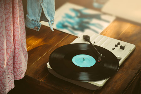 Media player and black vinyl record on the wooden table. Retro film look filter toned