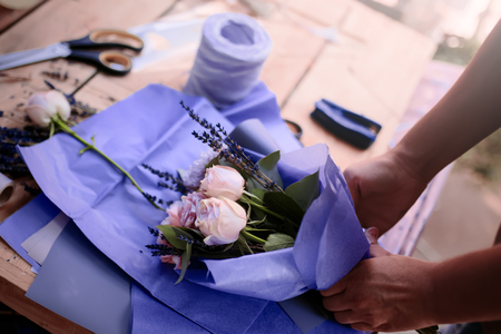 Woman is crafting rose flower bouquet on the wooden tableの写真素材