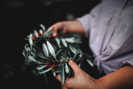 Woman is holding in the hands the wreath of flowers. Beautiful nature floral head crown. Trendy filter toned imageの写真素材