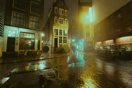 Amsterdam, Netherlands - March 5, 2020: People are walking on the street in Amsterdam city center old town at night in the rainのeditorial素材