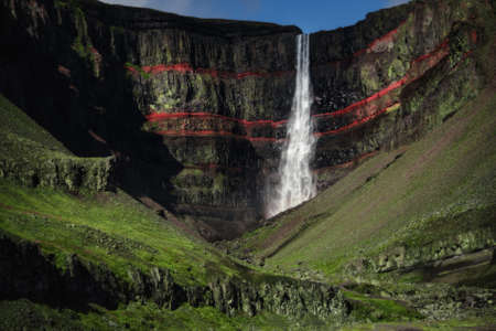 Hengifoss waterfall landscape in East Iceland. Red layers of clay between the basaltic layersの写真素材