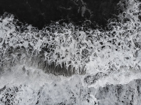 Abstract nature background. Aerial drone view of Reynisfjara Black Sand Beach and ocean waves in...