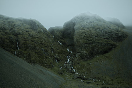Beautiful nature dramatic landscape in Iceland. Low clouds, fog on the mountains. Cold toned filterの写真素材