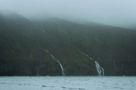 Beautiful nature dramatic landscape in Iceland. Low clouds, fog on the mountains. Cold toned filterの写真素材
