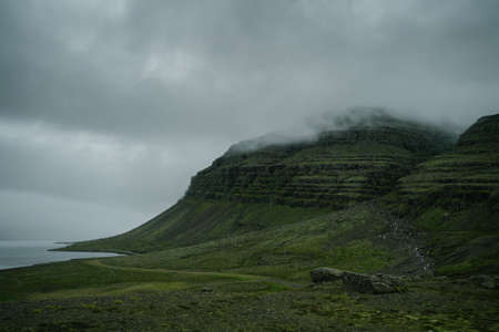 Beautiful nature dramatic landscape in Iceland. Low clouds, fog on the mountains. Cold toned filterの写真素材