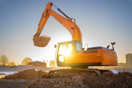 Orange color excavator on the construction site at sunset. Industrial imageの写真素材