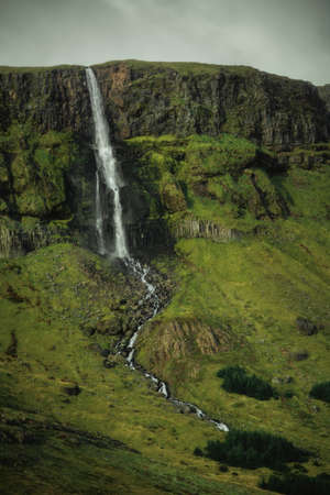Waterfall in green mountains in Iceland. Beautiful nature landscape in the dayの写真素材