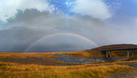 Panorama view of icelandic nature landscape. Rainbow after rain, road and river. West Iceland regionの写真素材