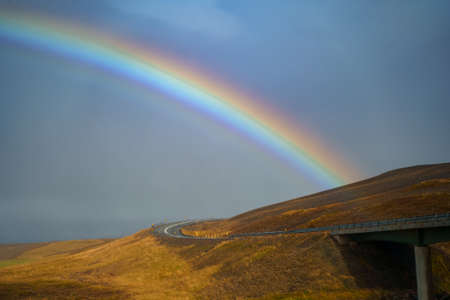 Icelandic nature landscape. Rainbow after rain, road and river. West Iceland regionの写真素材