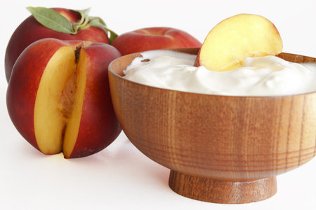 yogurt with peaches in a wooden bowlの写真素材