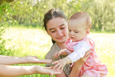 A teenager with a baby in her arms give the child to her motherの写真素材