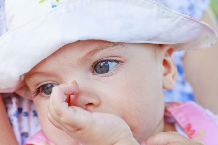 Thinking baby girl with her finger in mouthの写真素材