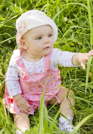 Curious baby girl on grassの写真素材