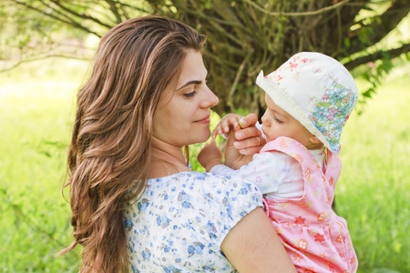 Baby girl with her mother giving a flowerの写真素材